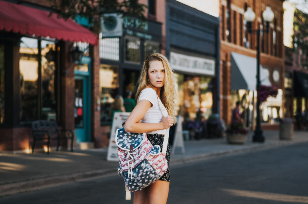 fourth of july girl with america backpack in front of shops
