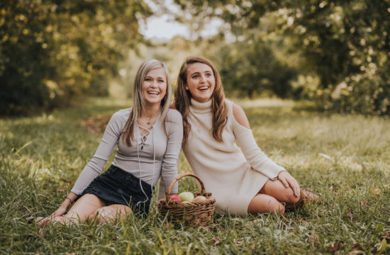 cute high school senior friends sitting in fall apple orchard laughing