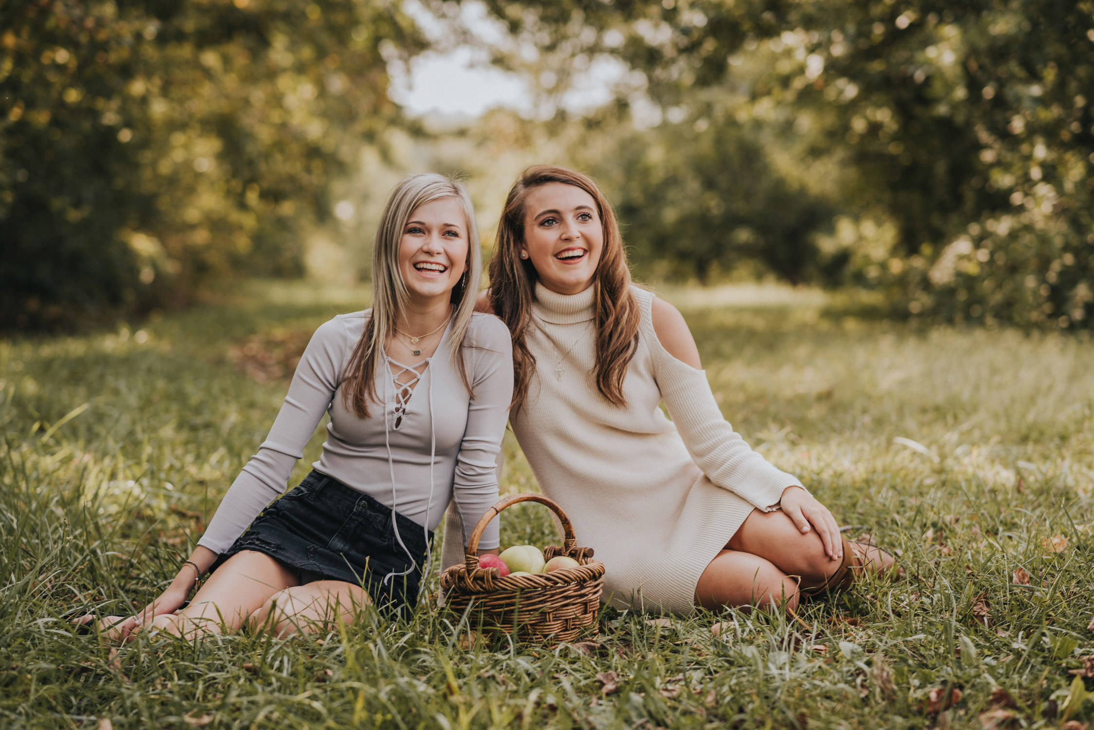 cute high school senior friends sitting in fall apple orchard laughing