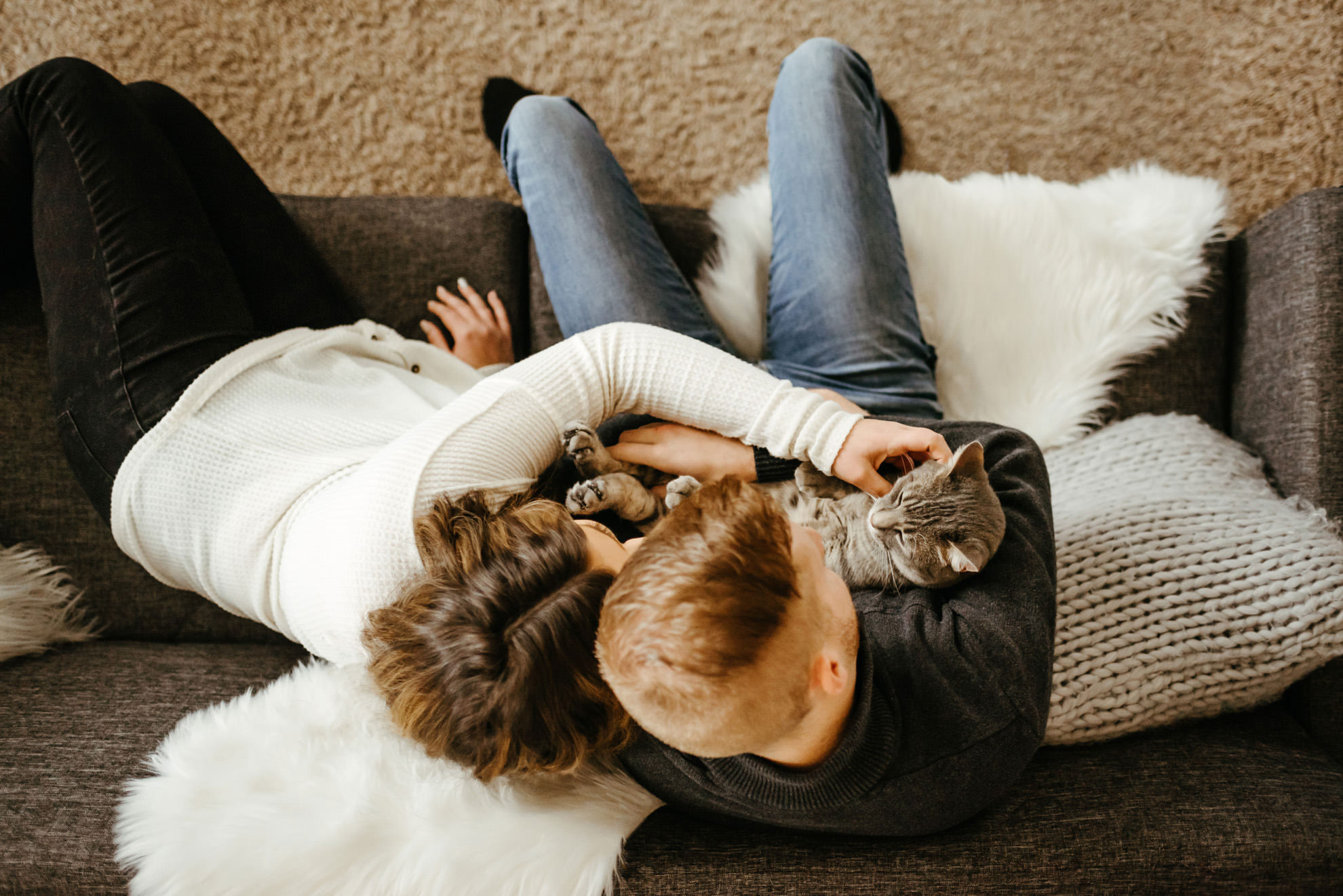 couple cuddling with cat on couch from above