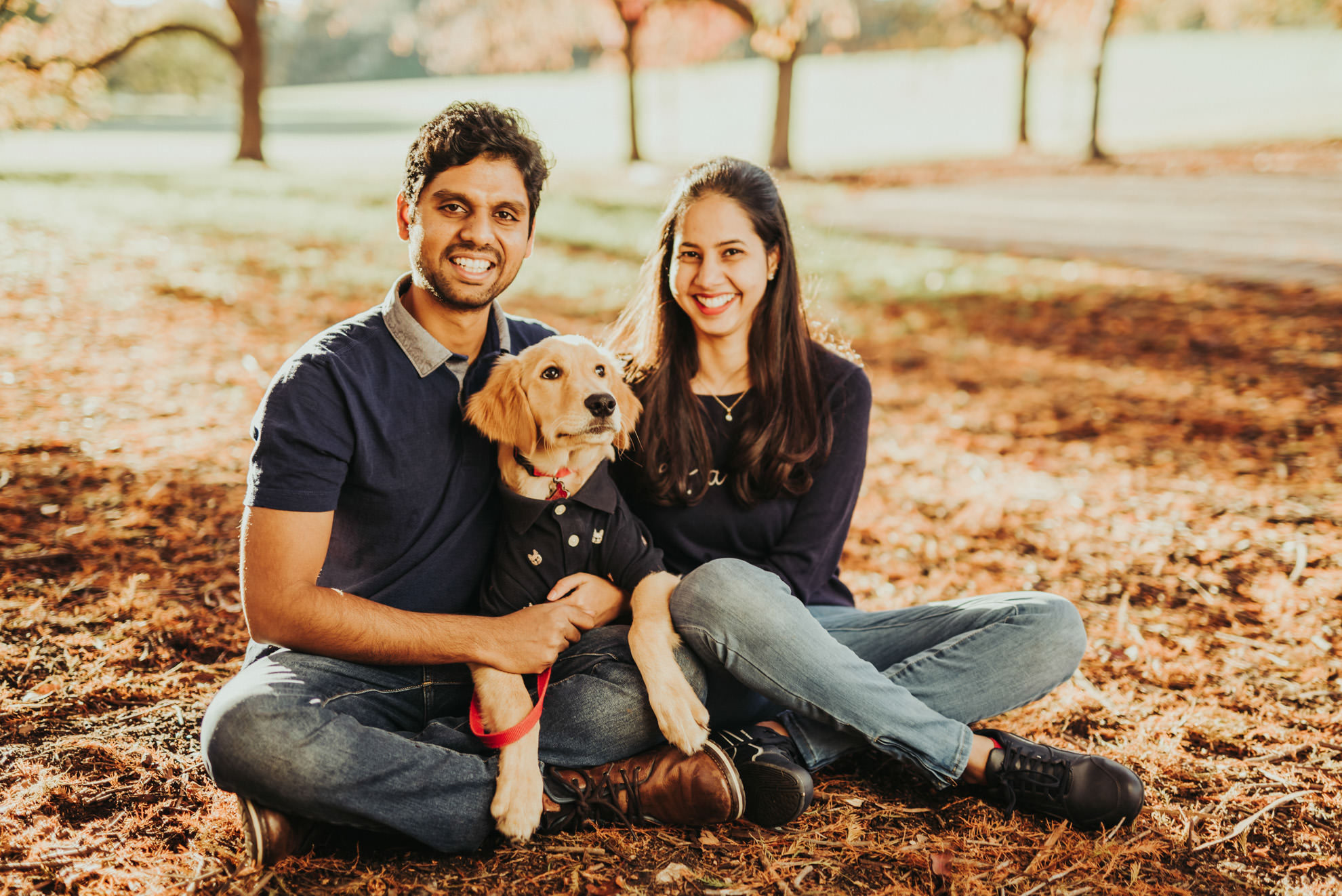 couple sitting on ground with puppy during fall