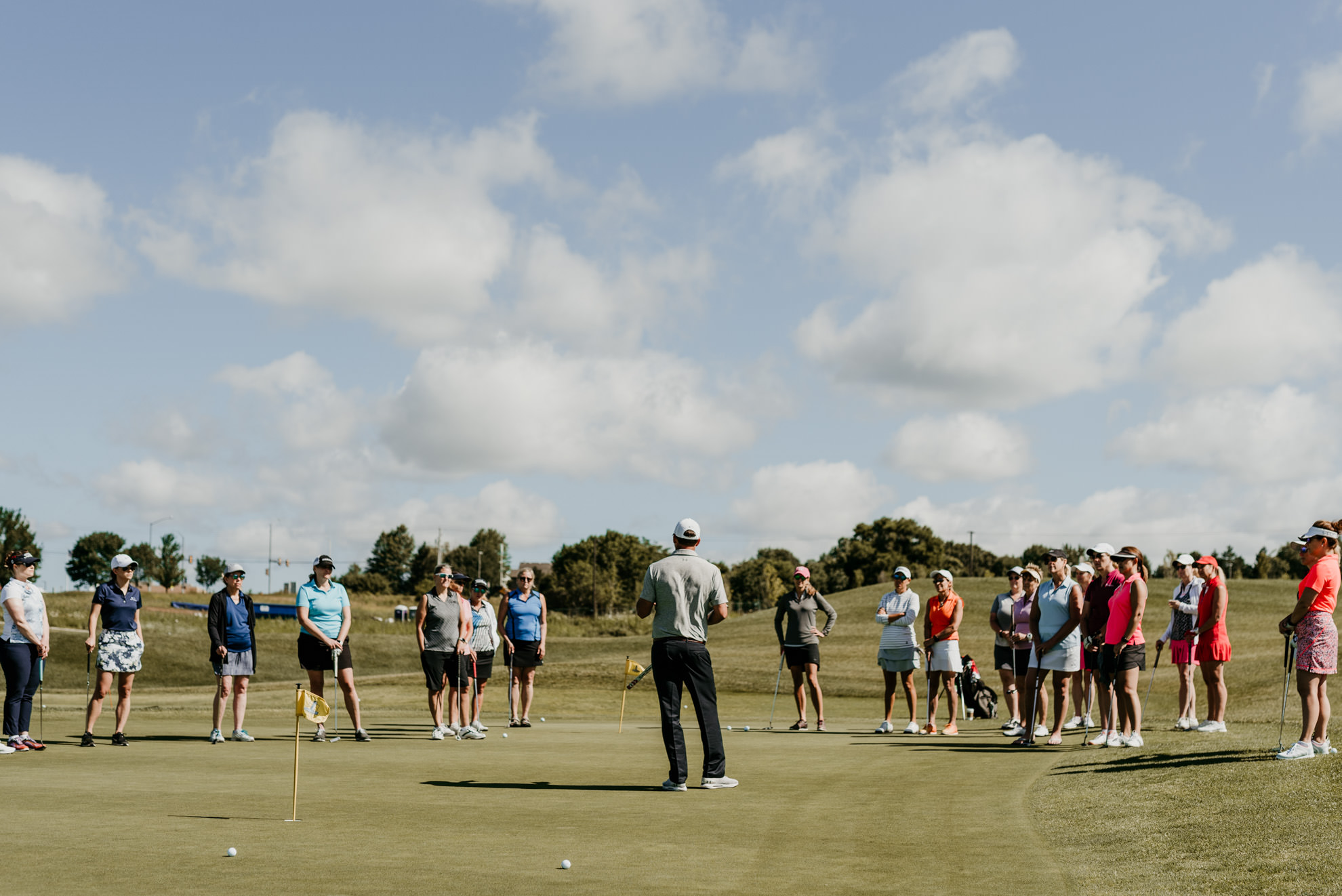man teaching group of women how to play golf