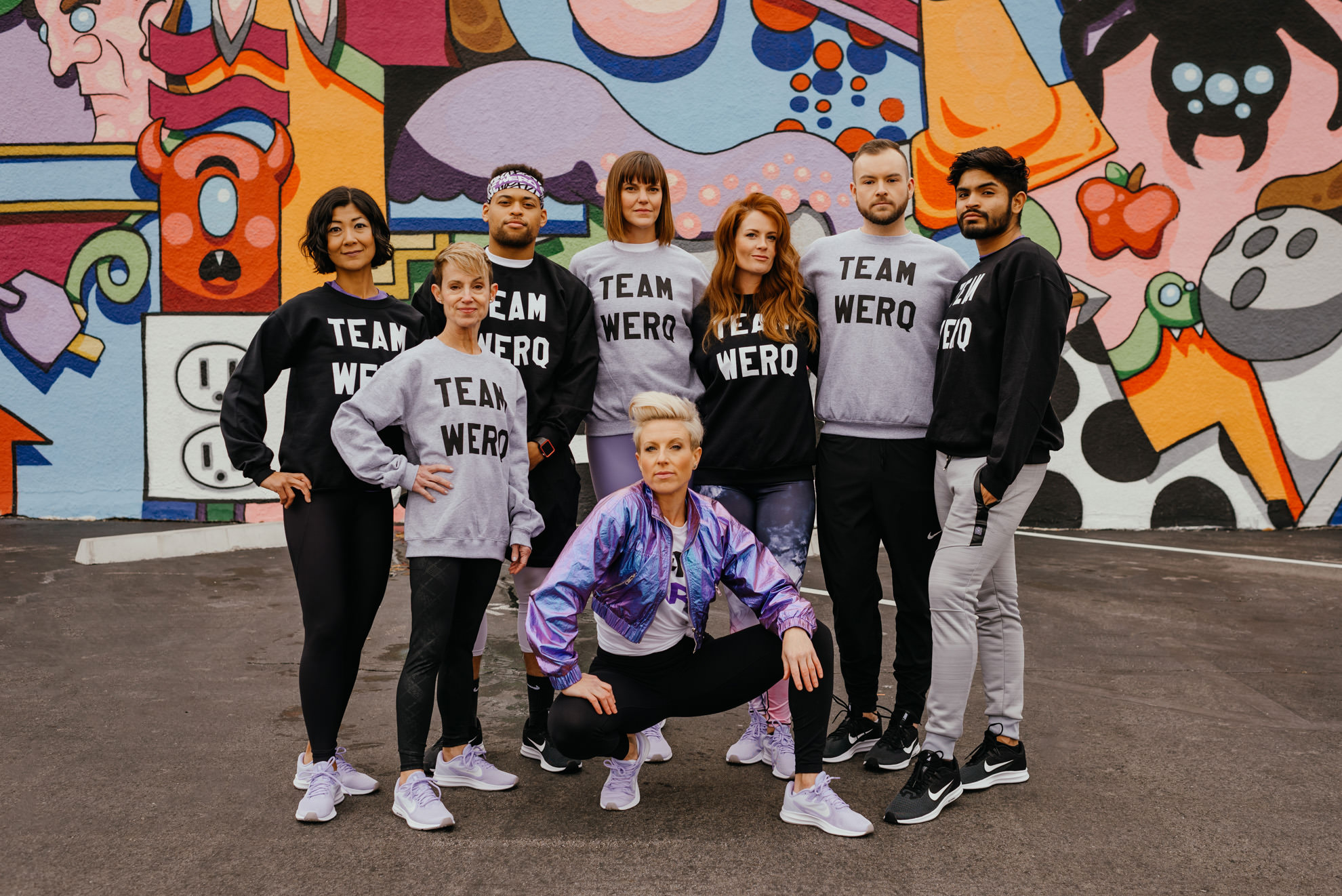 group of diverse people modeling fitness clothing in front of colorful mural