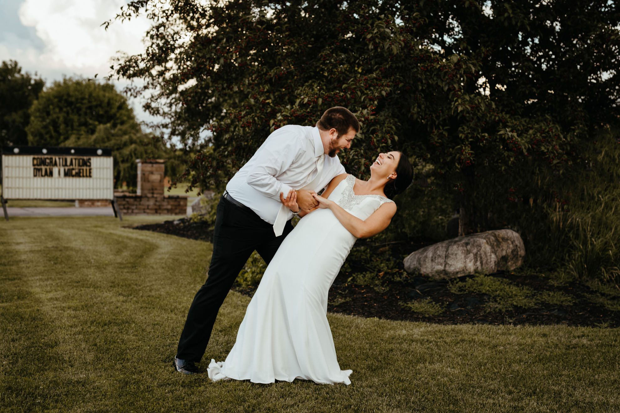 groom dipping bride while dancing in grass