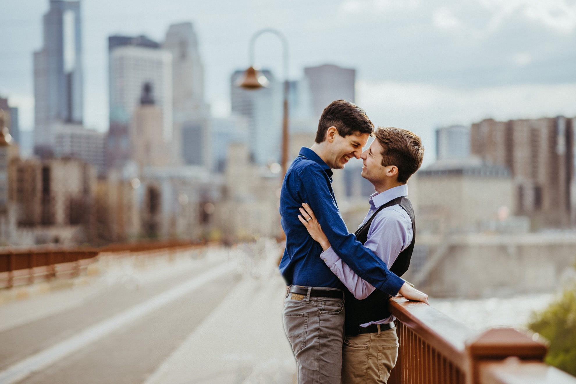 lgbt couple hugging on stone arch bridge in minneapolis