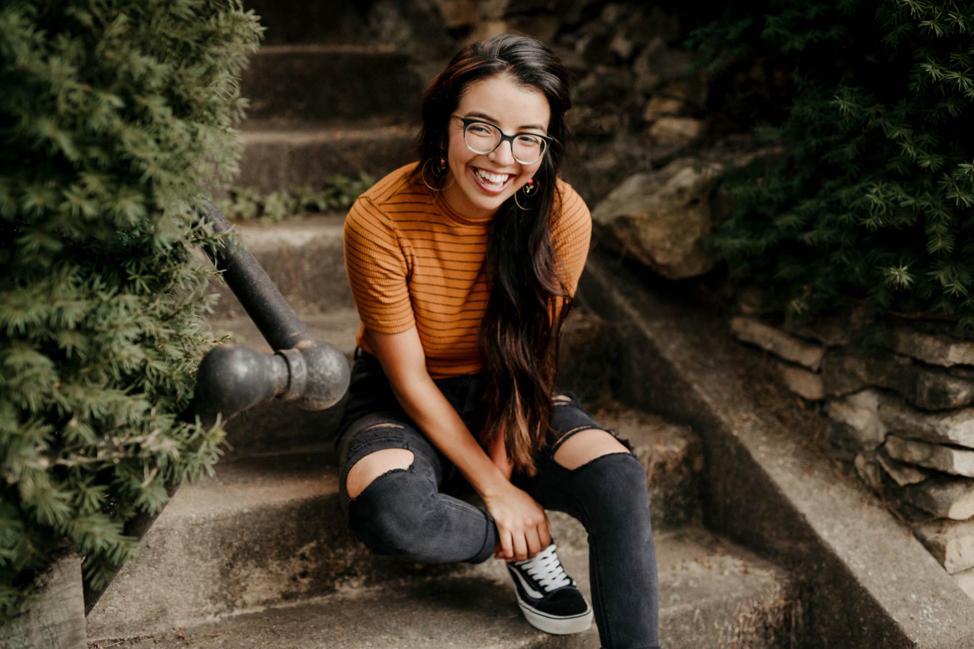 portrait of smiling woman sitting on sidewalk steps in summer