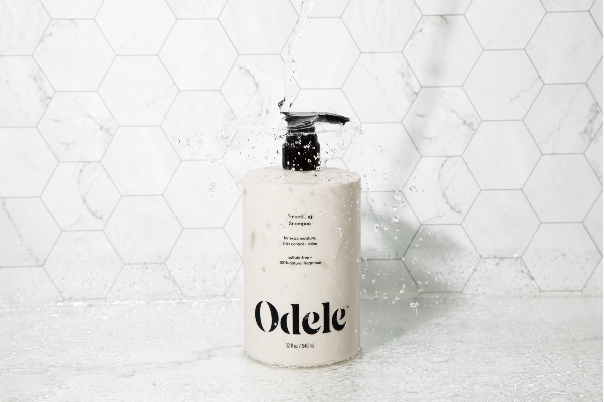 odele hair care product photo with water being poured on product in bathroom setting