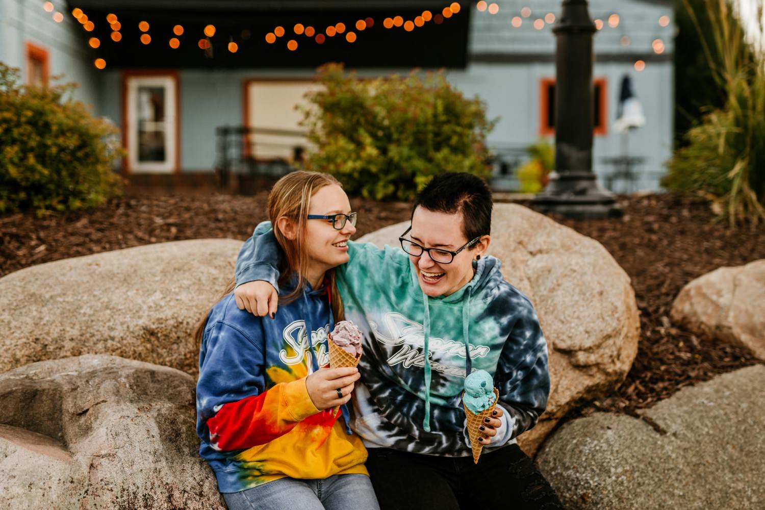 two girlfriends with ice cream cones laughing together outside cute ice cream shop